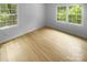 Bright, empty bedroom with hardwood floors, white walls, trim, and two windows with lots of natural light at 10931 Osprey Dr, Charlotte, NC 28226