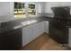 Kitchen with dark countertops and appliances, white cabinets, tile floors, and a window view at 10931 Osprey Dr, Charlotte, NC 28226