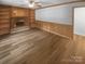 Cozy living room with hardwood floors, built-in bookshelves, a brick fireplace, and wood paneled walls at 10931 Osprey Dr, Charlotte, NC 28226