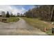 Long gravel driveway leading up to a home on a large, grassy lot with mature trees at 12143 Asbury Chapel Rd, Huntersville, NC 28078