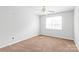 A bedroom with neutral walls, brown carpet, and a ceiling fan and large window at 12452 Stratfield Place Cir, Pineville, NC 28134