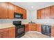 Kitchen with wood cabinets, black appliances, and laminate countertops at 12452 Stratfield Place Cir, Pineville, NC 28134