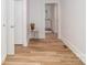 Hallway with wood-look flooring, white wainscoting, and view into kitchen and bathroom at 13414 Central Ave, Huntersville, NC 28078
