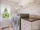 Well-lit laundry room with modern washer and dryer, countertop space, storage cabinets, and window at 184 Melbourne Dr, Fort Mill, SC 29708