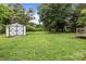 This backyard features a white shed, a large green lawn, and mature trees at 200 Southwood Park Rd, Mooresville, NC 28117