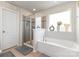 A spacious bathroom features an elegant soaking tub beneath a bright window, and a glass enclosed shower at 205 Falls Cove Dr, Troutman, NC 28166
