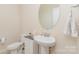 Half bathroom featuring a pedestal sink, round mirror, and neutral wall paint at 410 Alucio Ct, Matthews, NC 28104