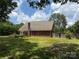 Backyard featuring grass, mature trees, and the brick exterior of the home at 4402 Poxon Ln, Monroe, NC 28110