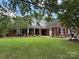 Charming red brick home with well-manicured lawn, mature trees, and covered front entry at 4402 Poxon Ln, Monroe, NC 28110