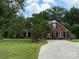 Charming red brick home with well-manicured lawn, mature trees, and paved driveway at 4402 Poxon Ln, Monroe, NC 28110