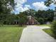 Attractive red brick home with well-manicured lawn and mature trees along paved driveway at 4402 Poxon Ln, Monroe, NC 28110