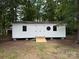 White outbuilding with double doors and small ramp, surrounded by trees at 4402 Poxon Ln, Monroe, NC 28110