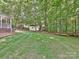 Lush backyard with a white storage shed surrounded by trees and greenery at 443 Hillcrest Dr, Harrisburg, NC 28075