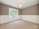 Cozy bedroom with neutral paint, wainscoting, plush carpeting, and bright natural light at 443 Hillcrest Dr, Harrisburg, NC 28075