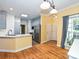 A kitchen features stainless steel appliances, a breakfast bar, and wood floors leading to the entry door at 443 Hillcrest Dr, Harrisburg, NC 28075