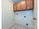 Functional laundry area with tiled floors, overhead storage, and washer-dryer hookups at 443 Hillcrest Dr, Harrisburg, NC 28075