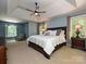 Bright main bedroom featuring a tray ceiling, large windows, and a cozy sitting area at 443 Hillcrest Dr, Harrisburg, NC 28075