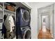 Well-organized laundry area with new stacked washer and dryer, storage shelves and a folding area at 5211 Londonderry Rd, Charlotte, NC 28210