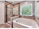 Bright bathroom featuring a glass-enclosed shower and a large soaking tub beneath a window at 5797 Mcclintock Dr, Denver, NC 28037