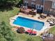 Aerial view of in-ground pool, deck, and outdoor furniture in landscaped backyard at 6523 Alba Rose Ln, Huntersville, NC 28078