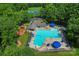 Community pool with playground, sun umbrellas, and lounging chairs surrounded by lush greenery at 10043 Elsenham Ln, Charlotte, NC 28269