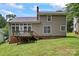 Back exterior featuring a well-maintained lawn, deck with chairs, and partial view of the house at 10043 Elsenham Ln, Charlotte, NC 28269
