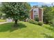Beautiful brick home with a well-manicured lawn and mature landscaping, including a large shade tree at 10043 Elsenham Ln, Charlotte, NC 28269