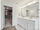 Bright bathroom featuring a dual sink vanity, large mirror, and a walk-in closet with custom shelving at 1008 Millbridge Pkwy, Waxhaw, NC 28173