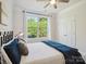 Bright bedroom with a ceiling fan, plush pillows on bed, and a view of lush green trees through the large window at 1008 Millbridge Pkwy, Waxhaw, NC 28173