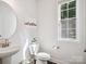 Clean powder room with a pedestal sink, wood floors, and a window that provides natural light at 1008 Millbridge Pkwy, Waxhaw, NC 28173
