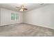Large bedroom with neutral carpet, ceiling fan, and window at 10606 Danesway Ln, Cornelius, NC 28031