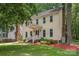 Charming two-story yellow home featuring a welcoming front porch and a lush, landscaped yard with mature trees at 10606 Danesway Ln, Cornelius, NC 28031