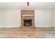 Bright living room featuring a classic brick fireplace and modern, light wood flooring, creating a cozy atmosphere at 10606 Danesway Ln, Cornelius, NC 28031