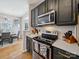 Well-equipped kitchen featuring stainless steel appliances, dark cabinets, tile backsplash, and hardwood flooring at 12320 Verdant Ct, Charlotte, NC 28273