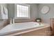 Bathroom featuring a standalone tub beneath a decorative window, surrounded by neutral tiling at 1241 Brough Hall Dr, Waxhaw, NC 28173