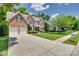 Stately brick home with a well-manicured lawn, mature landscaping, attached two-car garage, and a concrete driveway at 1241 Brough Hall Dr, Waxhaw, NC 28173