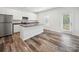 Bright kitchen featuring a center island, white cabinetry, stainless steel appliances and wood-look flooring at 125 Fosters Glen Pl, Mooresville, NC 28115
