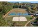 Aerial view of tennis courts, a sand volleyball court and playing field surrounded by mature trees at 131 Cherry Bark Dr, Mooresville, NC 28117