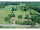 Aerial view of a brick home with lush landscaping on a property with a barn and surrounding by open green space at 157 Blackberry Ln, Taylorsville, NC 28681
