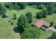 Aerial view of a brick home with a brown roof, surrounded by lush green pasture and mature trees at 157 Blackberry Ln, Taylorsville, NC 28681
