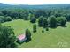 Aerial view of a barn surrounded by large green field, with wooded areas and mountain views at 157 Blackberry Ln, Taylorsville, NC 28681