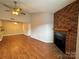 Open-concept living room with fireplace, ceiling fan, and hardwood style flooring at 1600 Sharon W Rd # 16, Charlotte, NC 28210