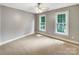 Cozy bedroom featuring neutral walls, soft carpet, and two large windows for ample light at 2027 Brook View Ct, Matthews, NC 28104