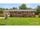 A backyard view featuring a brick home, a grill, and a flat grassy lawn at 2476 Cane Mill Rd, Lancaster, SC 29720