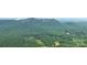 An aerial view of the property surrounded by lush, green forest and mountains in the distance at 2915 Old Stage Rd, Gastonia, NC 28052