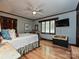 Well-lit bedroom with hardwood floors, ceiling fan, TV, and dark stained wood trim at 2915 Old Stage Rd, Gastonia, NC 28052