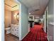 Hallway leading to a half bathroom and a basement recreation area on a red plaid carpet at 2915 Old Stage Rd, Gastonia, NC 28052