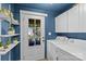 Blue laundry room featuring white cabinets, plants on shelves, and modern appliances at 3035 Florida Ave, Charlotte, NC 28205