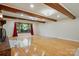 Open living room with wood beams, hardwood floors, exposed brick fireplace, and large windows at 3135 Lake Shore S Rd, Denver, NC 28037