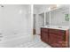 Well-lit bathroom with a vanity sink, a bathtub, and white tile walls and flooring at 317 Campus St, Charlotte, NC 28216